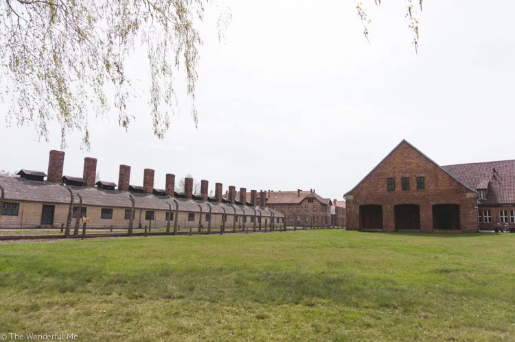 The fenced wall and one of the many cold brick buildings of the Auschwitz Concentration Camp, a must-visit attraction in Eastern Europe. 