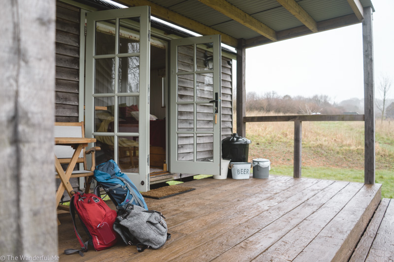 Backpacks are strewn across the Shepherd's Hut deck and you can see the recycling bins in the background. 