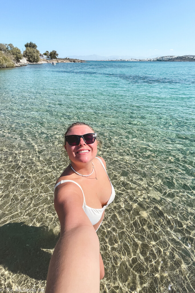 Sophie smiling up at the camera while in the crystal-clear, turquoise waters of Paralía Molos, a small yet beautiful beach on the island of Paros. 