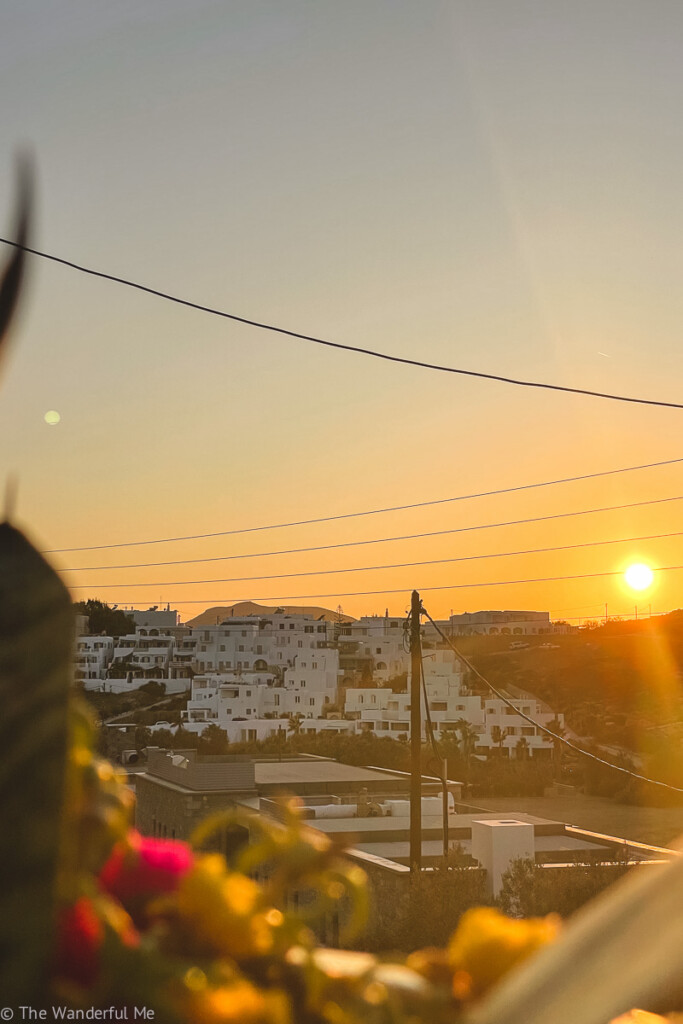 Sunset on the island of Paros in Greece, with a view of white-washed buildings in the distance. 